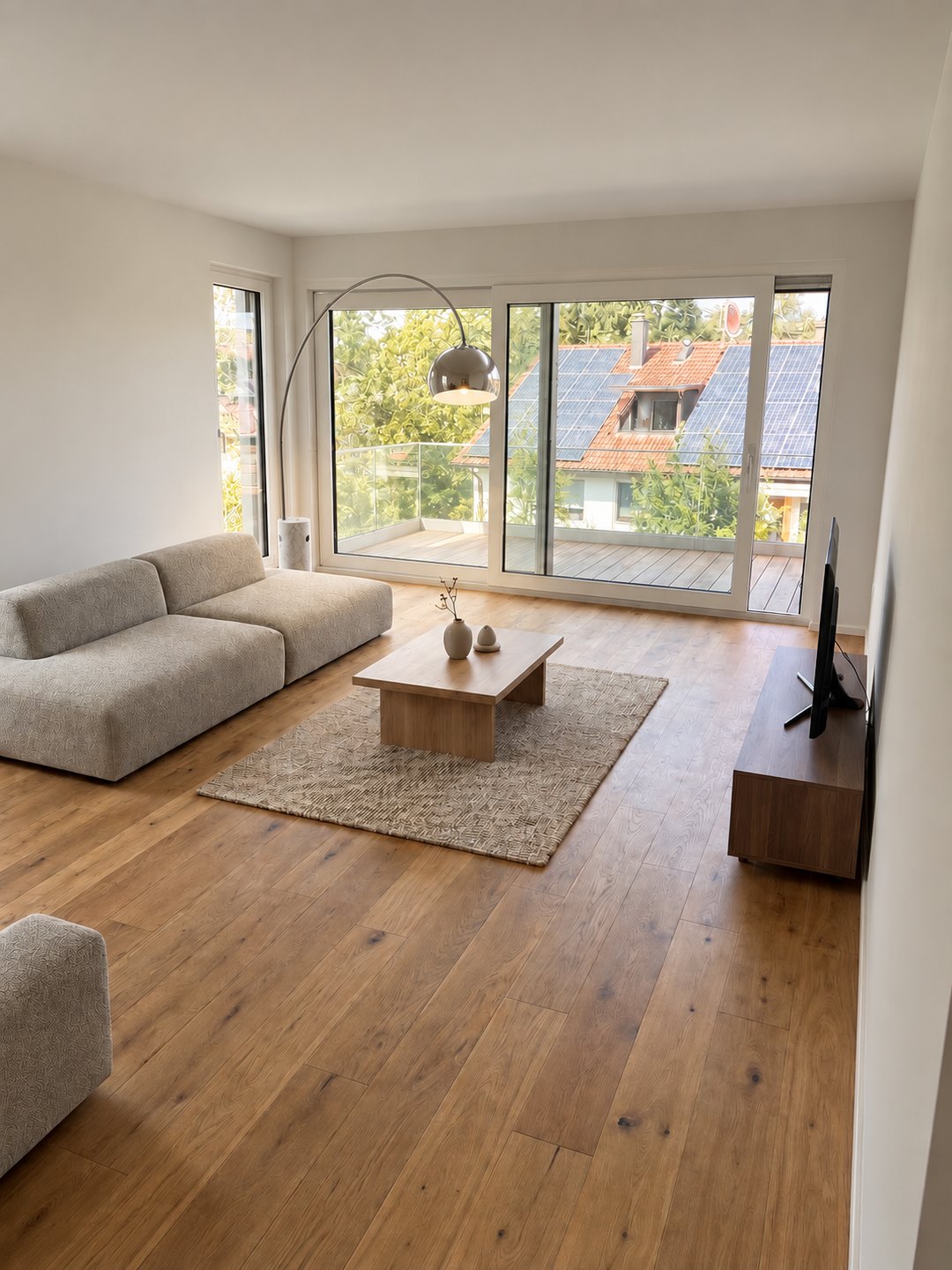 Wohnzimmer der Wohnung No_05 mit Eichenparkett und bodentiefen Fenstern zur Terrasse